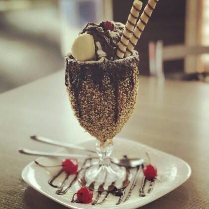 Ice cream sundae with chocolate syrup, cookies, nuts, and cherries